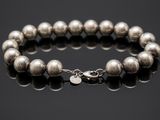 a silver beaded bracelet on a black surface