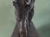 bronze statue of a tiger on a wooden base on a green background