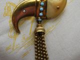 un gros plan sur un collier en or et turquoise orné d'une corne