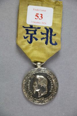 un gros plan d'une médaille posée sur une surface blanche, avec un ruban doré