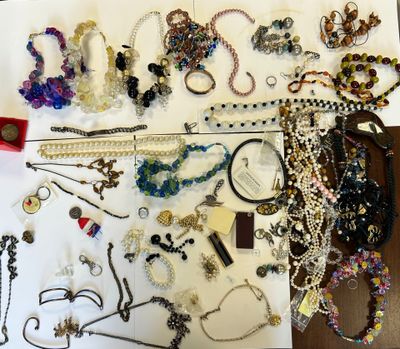 beaucoup de bijoux posés sur une table, à côté d'une paire de ciseaux