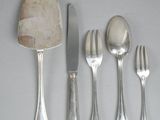 five forks, a spoon, and a knife on a table