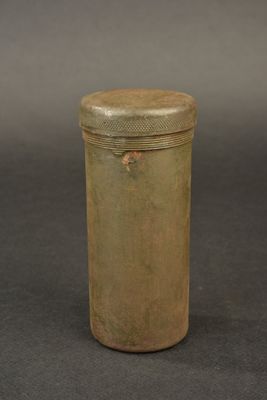 an old metal container with a wooden lid on a gray surface