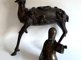 statue en bronze représentant un homme agenouillé à côté d'une statue de cerf