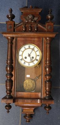 a wooden clock hanging on the wall on a tiled floor