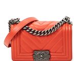 a small orange quilted bag with a chain strap