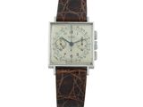 gros plan d'une montre sur une surface blanche avec un bracelet marron