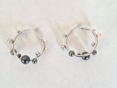 paire de boucles d'oreilles créoles en argent ornées de perles noires sur fond blanc