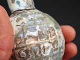 a person holding a small vase in their hand