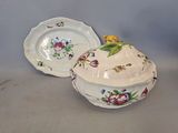 two plates and a bowl with a lid on a table