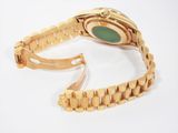 a gold watch with a green face on a white background