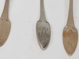 three silver spoons with a monogram on them sitting next to each other