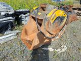 un bulldozer jaune posé par terre à côté d'un tas de bois