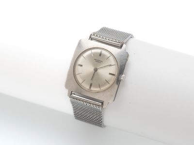 une montre-bracelet en argent posée sur une serviette blanche