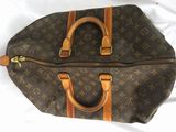 louis vuittou bag on a bed with a white sheet