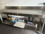 une table en acier inoxydable sur laquelle est posée une planche à découper