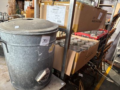 a large metal trash can sitting on a cart in a warehouse