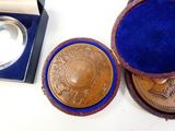 a gold medal sitting in a blue box next to a silver medal