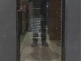 an image of a glass door refrigerator with a man standing in the background