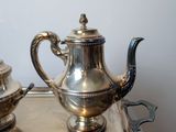 two silver teapots sitting on a tray on a table