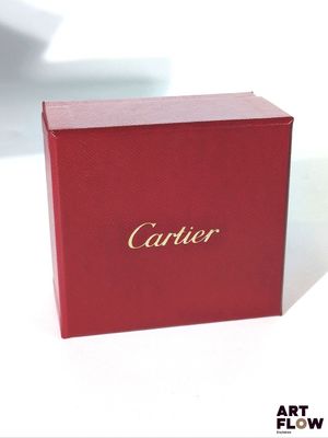 une boîte rouge ornée d'inscriptions dorées, posée sur une surface blanche