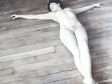 black and white photograph of a naked woman laying on a wooden floor