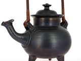 a black tea pot with a wooden handle on a white surface