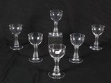 six clear wine glasses are lined up on a black background