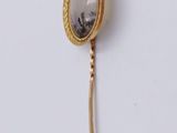 a gold brooch with a picture of a woman on it