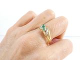 a person ' s hand holding a ring with a green stone on it