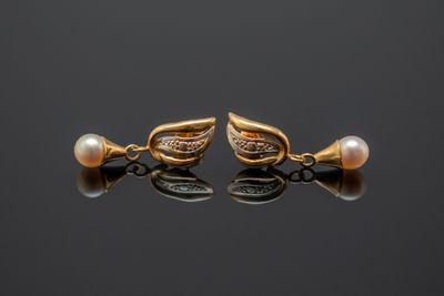 une paire de boucles d'oreilles en or ornées de perles sur un fond noir