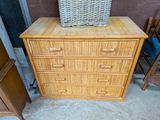 a wicker chest of drawers with a basket on top of it