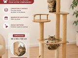 Le chat est assis tout en haut de l'arbre à chat dans le salon.