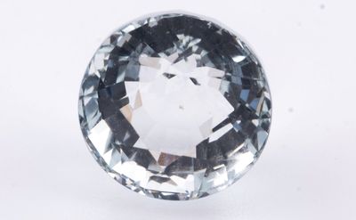 un gros plan d'un diamant bleu à facettes posé sur une surface blanche