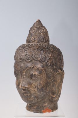 statue of a head of a buddha on a stand on a white surface