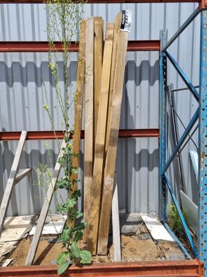 Plusieurs morceaux de bois sont empilés sur une palette devant un bâtiment