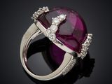 a close up of a ring with a ruby stone and diamonds