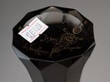 a black glass vase with writing on it on a table
