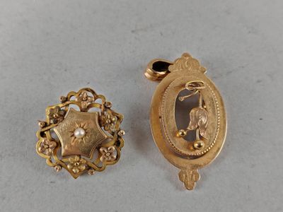 two pieces of gold jewelry on a table with a white background
