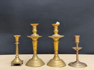 three brass candlesticks on a table with a black background