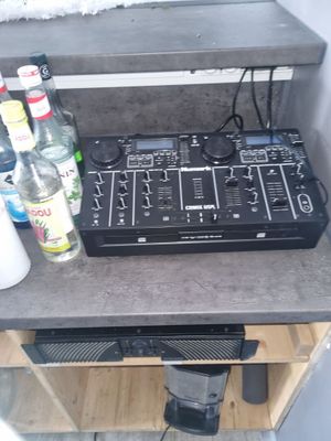 une table sur laquelle se trouvent une table de mixage de DJ et des bouteilles d'alcool