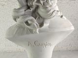 a white bust of a woman with long hair on a blue and white pedestal