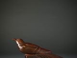 a wooden bird sitting on top of a piece of wood