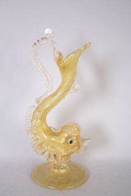 une figurine en verre représentant un poisson jaune, posée sur un socle