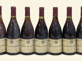 six bottles of wine are lined up in a row on a white surface