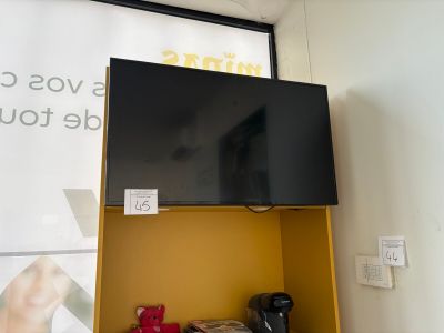 a television mounted on a yellow shelf in the corner of a room