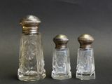 trois salières et poivrières en verre posées les unes à côté des autres sur une table