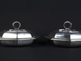 pair of silverplated dishes with lids on black background