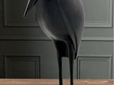 une statue d'oiseau noir posée sur une table en bois