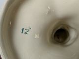 a close up of a person holding a vase with a number on it